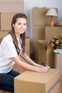 A woman sitting on the floor in her rented apartment in Katy TX, surrounded by moving boxes.