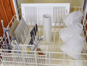 An apartment dishwasher stocked with a basket of cleaning supplies.