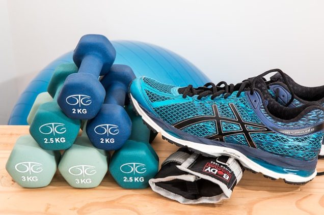 A pair of asics shoes and a pair of dumbbells on a wooden table in an apartment for rent in Katy.