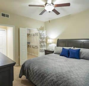 A cozy bedroom in one of the Katy Texas Apartments, complete with a comforting ceiling fan and a comfortable bed.