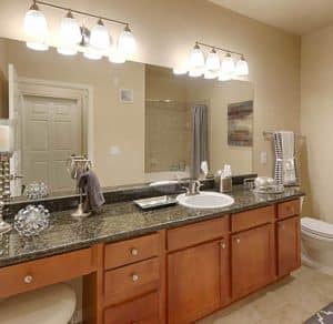 A Katy Texas apartment with a bathroom featuring granite counter tops and a large mirror.